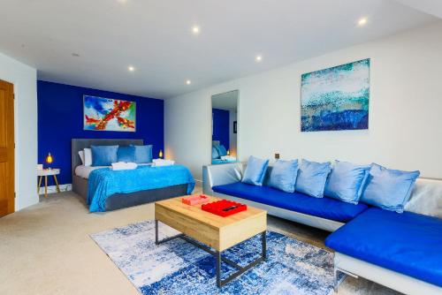 a blue living room with a couch and a bed at Beachcliff Rooms & Apartments in Cardiff
