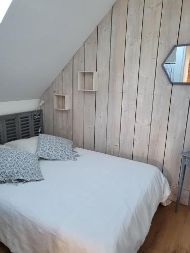 a bedroom with a white bed with a wooden wall at La Forge, gîte familial,à Sainte Mère Eglise in Sainte-Mère-Église