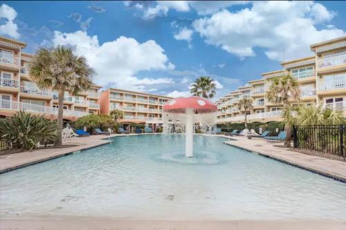 a fountain with an umbrella in the middle of a pool at Ocean & Pool View - Hot Tub - 2 Pools - Gym - Tennis ct - Shoreline Stays 10 in Galveston