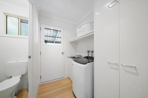 a white bathroom with a sink and a toilet at Flynns Beach Caravan Park in Port Macquarie