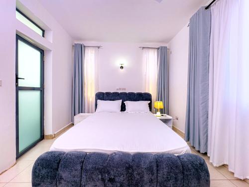 a bedroom with a large bed with a blue couch at Diani hideouts in Kwale