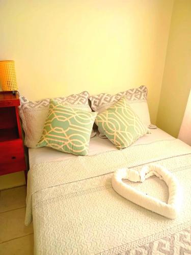a bed with a heart shaped pillow on it at Juju's Cottage with magnificent views in Laborie