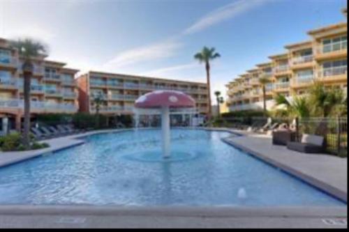 a large swimming pool with an umbrella in a resort at Ocean Views - Heated Pool - Hot Tub - Corner Unit - steps to beach - SS 29 in Galveston