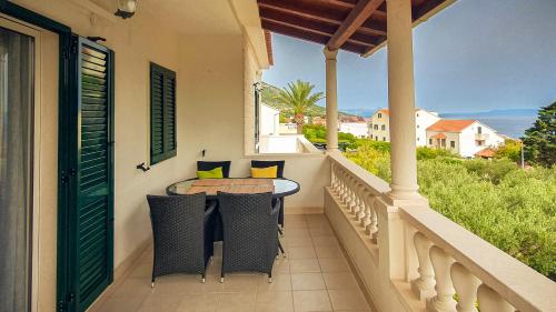 a porch with a table and chairs on a balcony at Apartmani Marijana in Bol