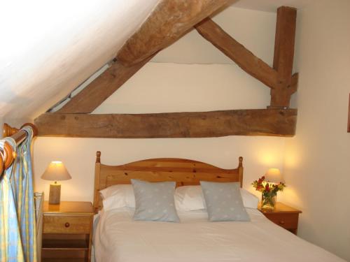 a bedroom with a white bed with wooden beams at Fosbroke Cottage in Bidford