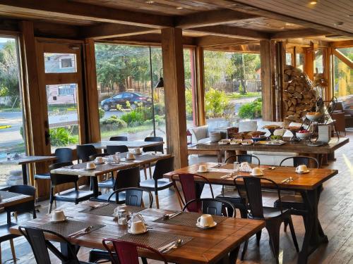 a restaurant with wooden tables and chairs and windows at Hotel Rangi Pucon in Pucón