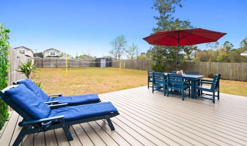a deck with two chairs and a table with an umbrella at New Home with Fenced Yard Large Deck & Fire Pit in Navarre
