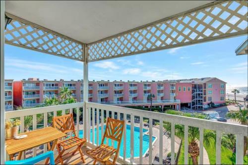 a balcony with a table and chairs and a pool at Ocean & Pool View - Top Floor - 2 Pools - Hot Tub - GYM - Tennis ct - SS03 in Galveston