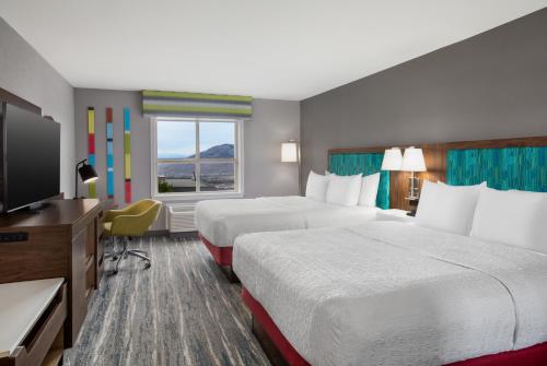 a hotel room with two beds and a flat screen tv at Hampton Inn by Hilton Kamloops in Kamloops
