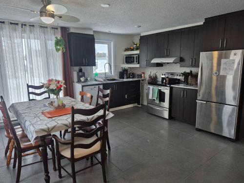 a kitchen with a table with chairs and a refrigerator at Logis des prodiges - Le 777 in Rouyn-Noranda