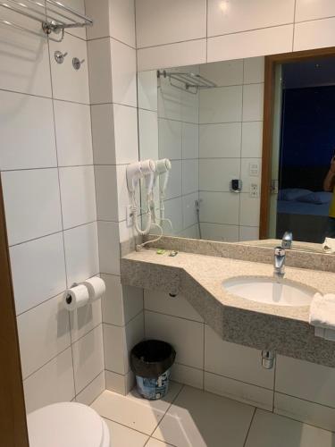 a bathroom with a sink and a toilet and a mirror at 701 - Flat Temporada em Goiania-proximo ao Parque Areião in Goiânia