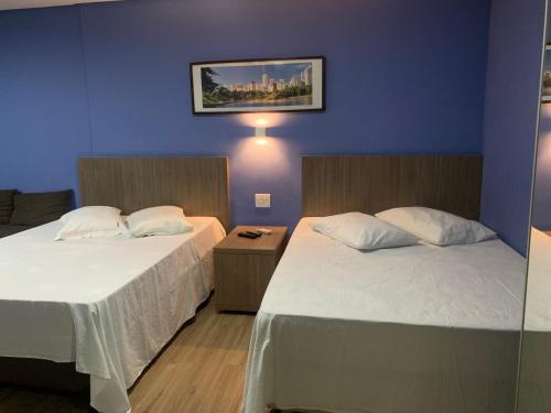 two beds in a room with blue walls at 701 - Flat Temporada em Goiania-proximo ao Parque Areião in Goiânia