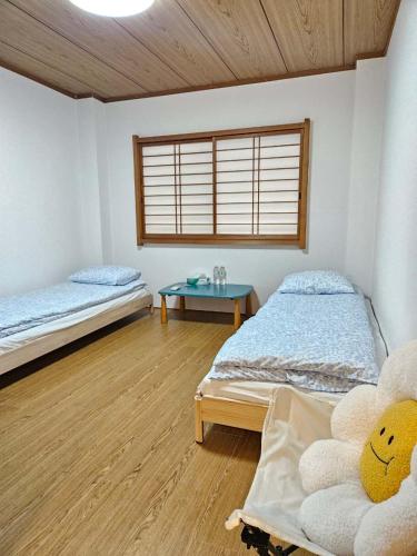 a room with two beds and a table in it at Kobe Youth Hostel in Kobe