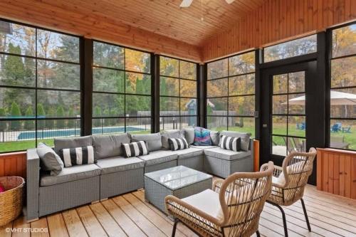 a screened in porch with a couch and chairs at The Dakota by Juniper Holiday + Home in Union Pier