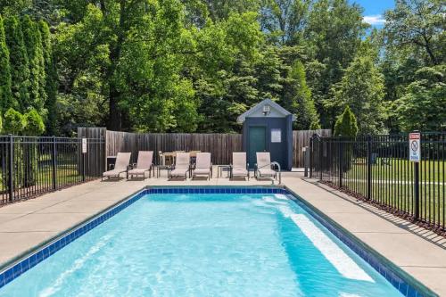 a swimming pool with chairs and a fence at The Dakota by Juniper Holiday + Home in Union Pier