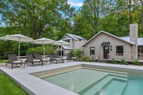a swimming pool with chairs and umbrellas next to a house at Townie 3 - The Moss by Juniper Holiday + Home in Union Pier