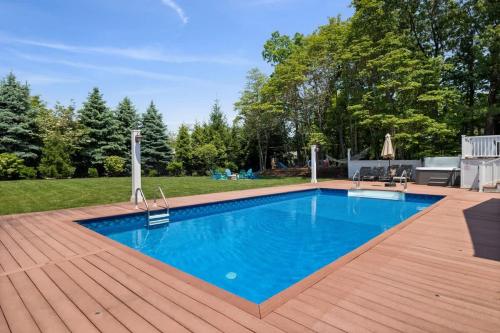 a swimming pool on a wooden deck next to a yard at Main Destination by Juniper Holiday + Home in Grand Beach