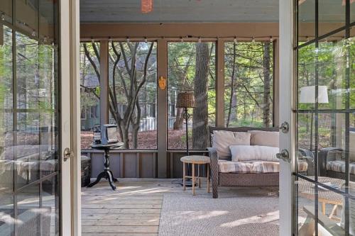 a screened in porch with a couch and a table at Deer Haus by Juniper Holiday + Home in New Buffalo
