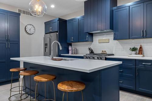 a kitchen with blue cabinets and a sink and stools at The Happy Place by Juniper Holiday + Home in Union Pier