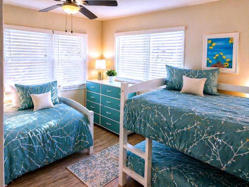 a bedroom with two beds and a dresser and windows at CasaViva Play - 3BR 1BA, Private Deck & City Views, Firepit, Kids Playset - Walk to Hillcrest & North Park, Near Zoo, SeaWorld & Beaches in San Diego
