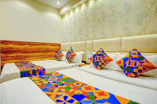 a hotel room with two beds with colorful pillows at Hotel Indore Palace Nagpada in Mumbai