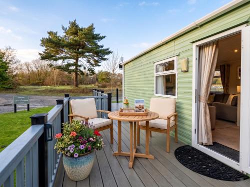 a green caravan with a table and chairs on a deck at 2 Bedroom Lakeview Lodge - Ensuite & Balcony Deck in Carnforth