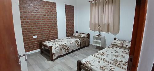 a bedroom with two beds and a brick wall at Cabañas Termales in Termas de Río Hondo