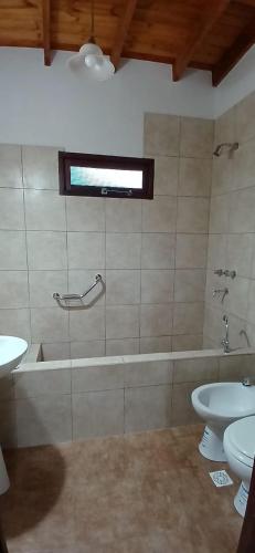 a bathroom with a tub and a toilet and a sink at Cabañas Termales in Termas de Río Hondo