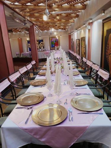 a long table with white and gold plates and napkins at Hotel Raices in Ambato