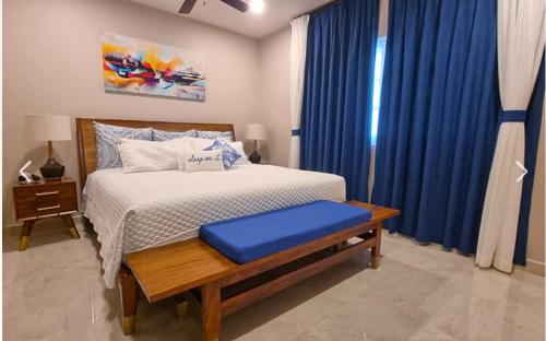 a bedroom with a bed with blue curtains and a table at Escape to Paradise in Tangolunda