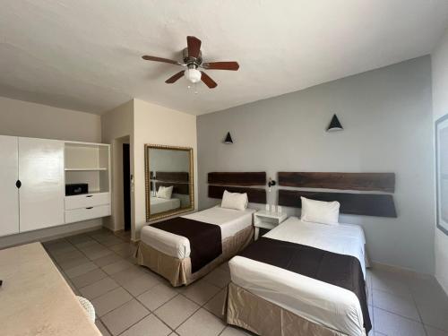 a bedroom with two beds and a ceiling fan at Days Inn by Wyndham Playa del Carmen in Playa del Carmen