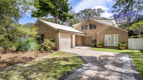 a house with a garage and a driveway at Gemburra By Holidayco in Pearl Beach