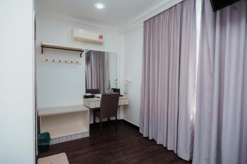 a room with a desk and a chair and a window at Pandan Inn Boutique Hotel in Kota Bharu