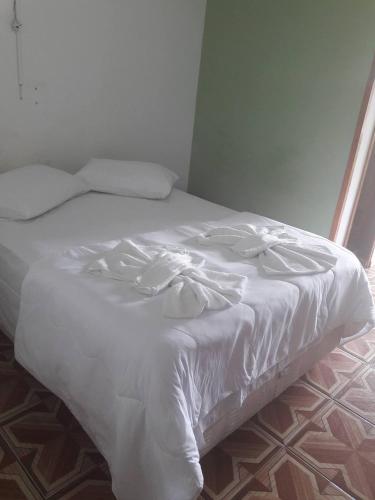 a white bed with white sheets and pillows at Pousada Miniférico in Campos do Jordão