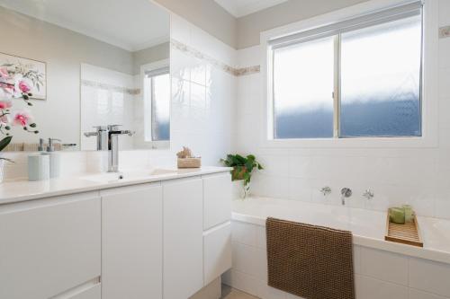 a white bathroom with a sink and a tub at Ohana Coastal Escape in Rosebud