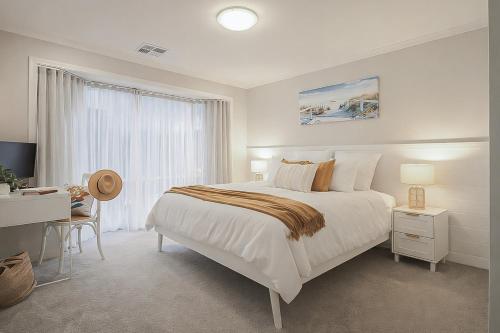 a white bedroom with a bed and a desk at Ohana Coastal Escape in Rosebud