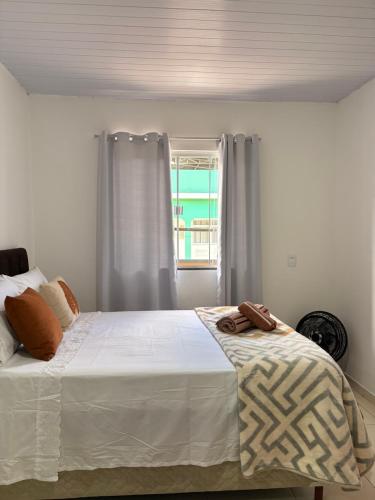 a bedroom with a white bed with a window at Doce Lar Alto Caparaó in Caparaó Velho