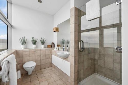 a bathroom with a toilet and a sink and a shower at U Suites at The Links in Paraparaumu