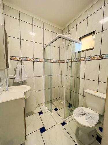 a bathroom with a toilet and a glass shower at Pousada Mel e Mar in Penha