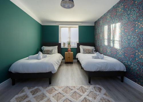 two beds in a room with blue walls at Private 2 Bed Escape with Huge Parking in Ely