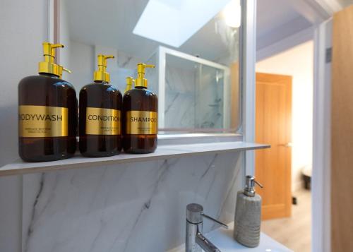 four bottles of wine sitting on a shelf next to a mirror at Private 2 Bed Escape with Huge Parking in Ely