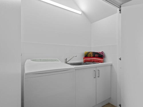 a kitchen with white cabinets and a sink at Esplanade Escape in Indented Head