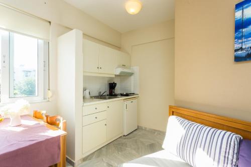 a kitchen with white cabinets and a bed in a room at Radamanthy's Hotel Apartments in Sfakaki