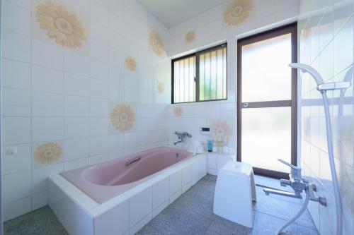 a bathroom with a pink tub and a window at ようこそ月の宿へ in Shindembaru
