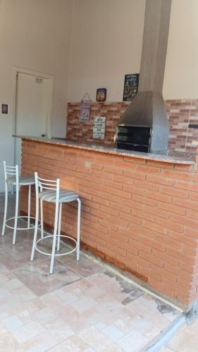 a brick counter with two chairs and a stove at Recanto Sossego Wi-Fi 3 quartos 3 banheiros 2 chuveiros Espaço amplo churrasqueira in Espirito Santo Do Pinhal