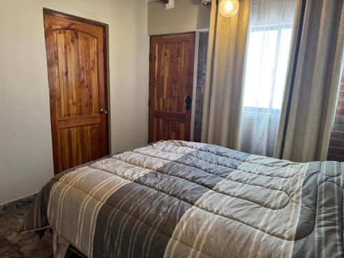 a bedroom with a bed and a window and a door at conixia in San Pedro de Atacama