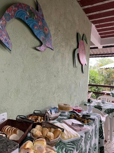 a table with bread and pastries and a dolphin on the wall at Pousada Encanto da Ilha in Praia de Araçatiba