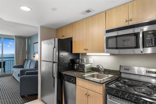 a kitchen with stainless steel appliances and a living room at Experience the ultimate beachfront lifestyle at Oceans One 1 Bdr with three queen beds in Myrtle Beach