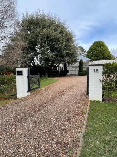 a gravel driveway with two white doors and a house at Oakwood Guesthouse in Berrima