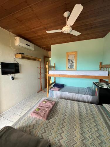 a room with two bunk beds and a ceiling fan at Pousada Encanto da Ilha in Praia de Araçatiba